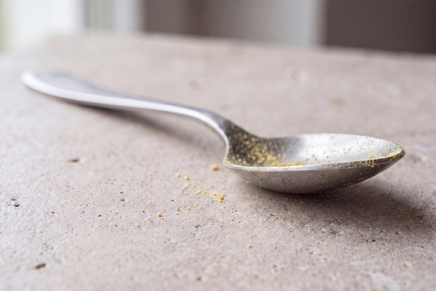 A teaspoon holding only a faint dusting of canary-yellow powder