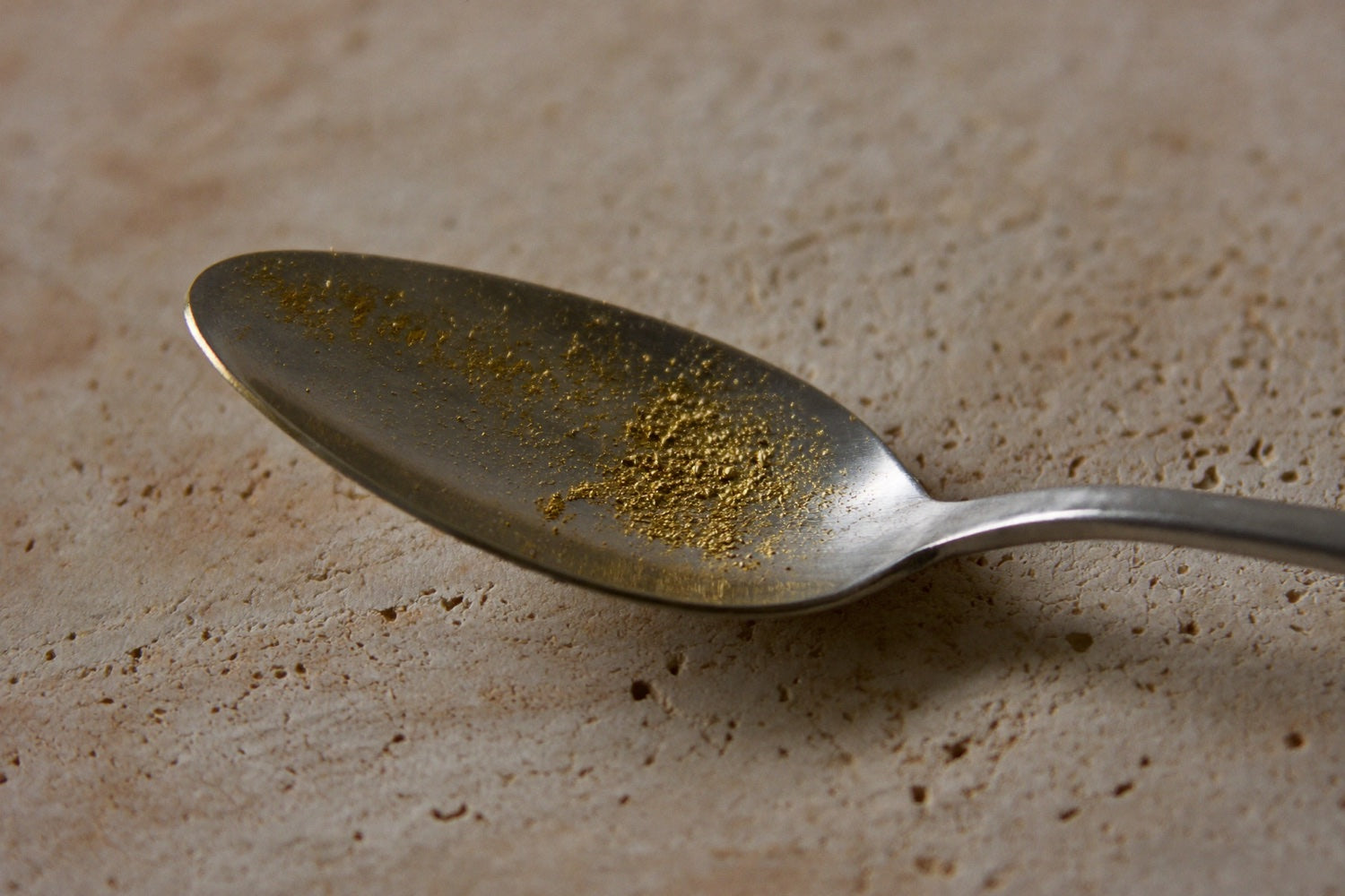 A spoon holding only a faint dusting of golden powder