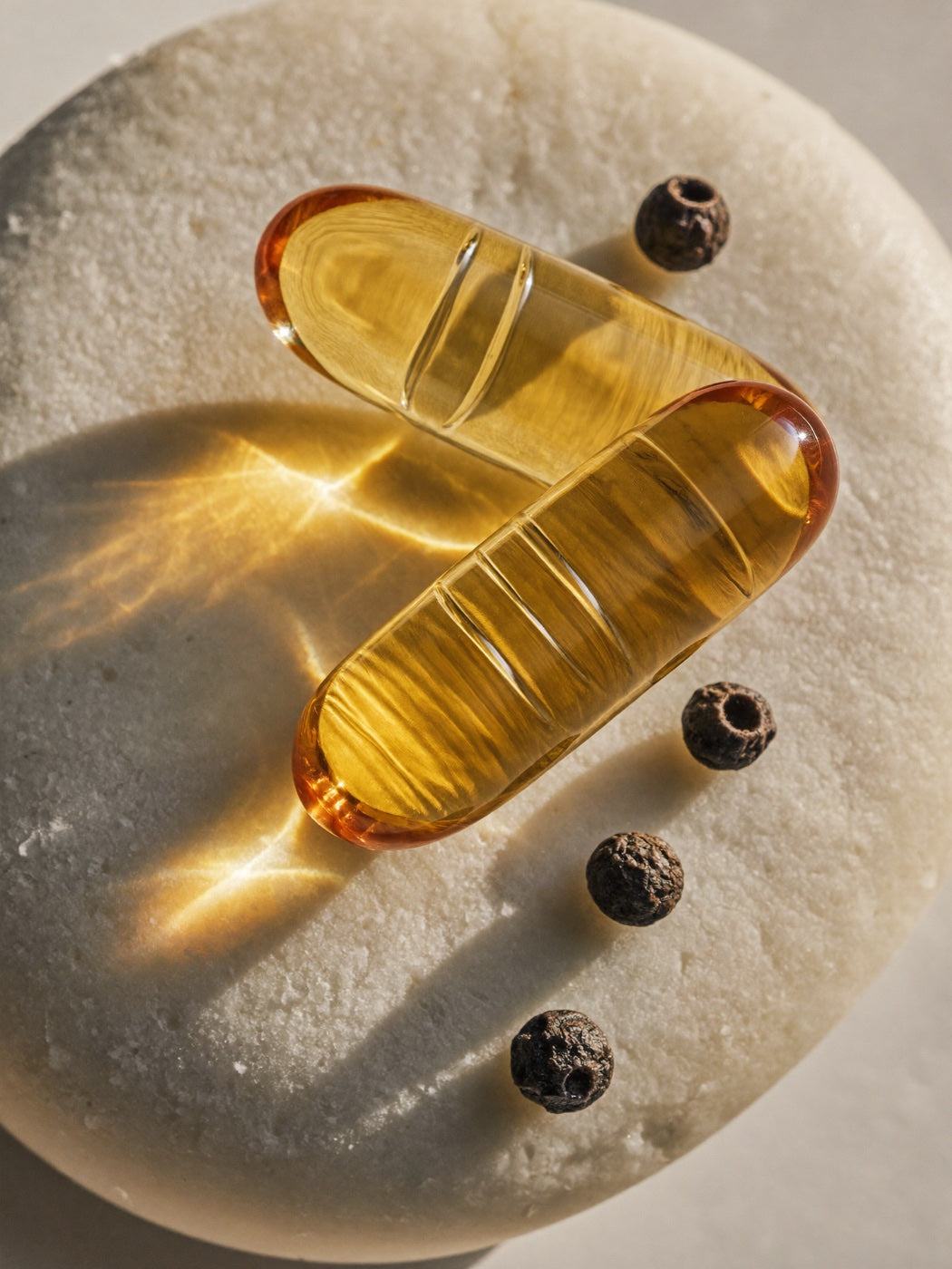 Amber-gold liposomal berberine capsules beside black peppercorns